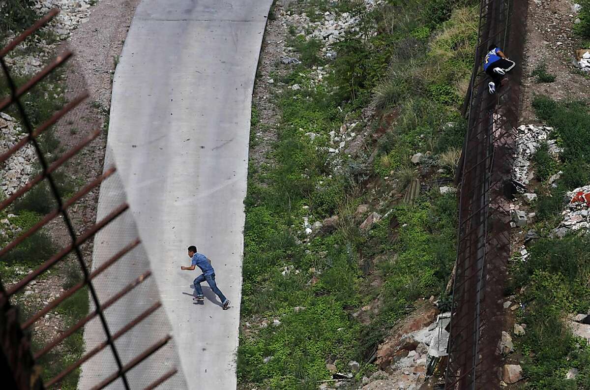 FILE - In this July 28, 2011 file photo, two men illegally cross the border fence separating Nogales, Ariz., and Nogales, Sonora, Mexico. The Supreme Court agreed Monday, Dec. 12, 2011 to rule on Arizona's controversial law targeting illegal immigrants. The justices said they will review a federal appeals court ruling that blocked several tough provisions in the Arizona law. One of those requires that police, while enforcing other laws, question a person's immigration status if officers suspect he is in the country illegally. (AP Photo/Jae C. Hong, File)