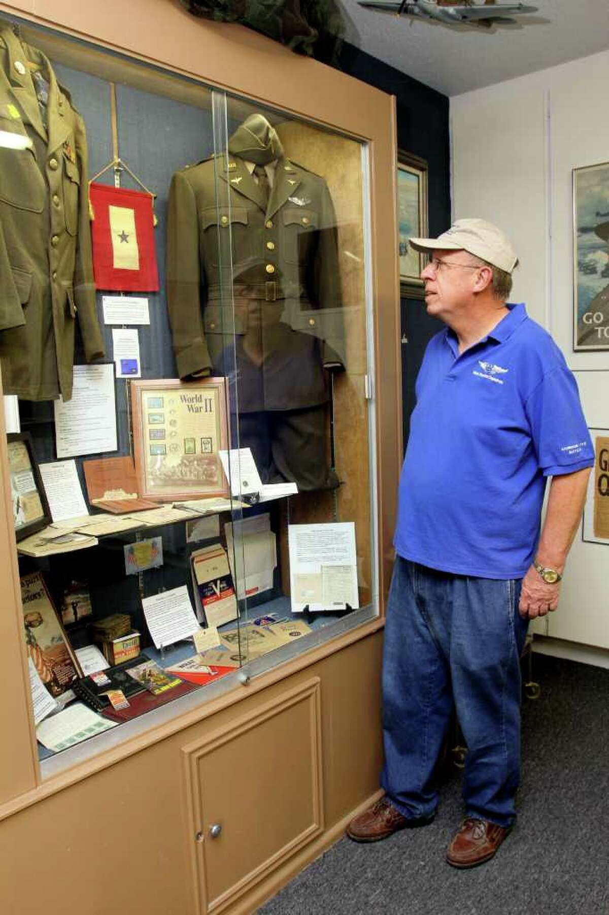 RELICS THAT TELL STORIES: Commemorative Air Force member, Sam Hoynes examines a World War II display case inside the group's museum. The case includes rationing stamps, coins. uniforms and civil defense bonds.