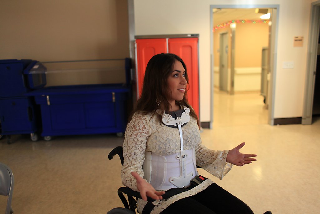 Katy Sharify (left), who received stem cell therapy before the study she  was part of was cancelled, moves between exercise machines in the Cypress  Semiconductor Spinal Cord Rehabilitation Gym with help from