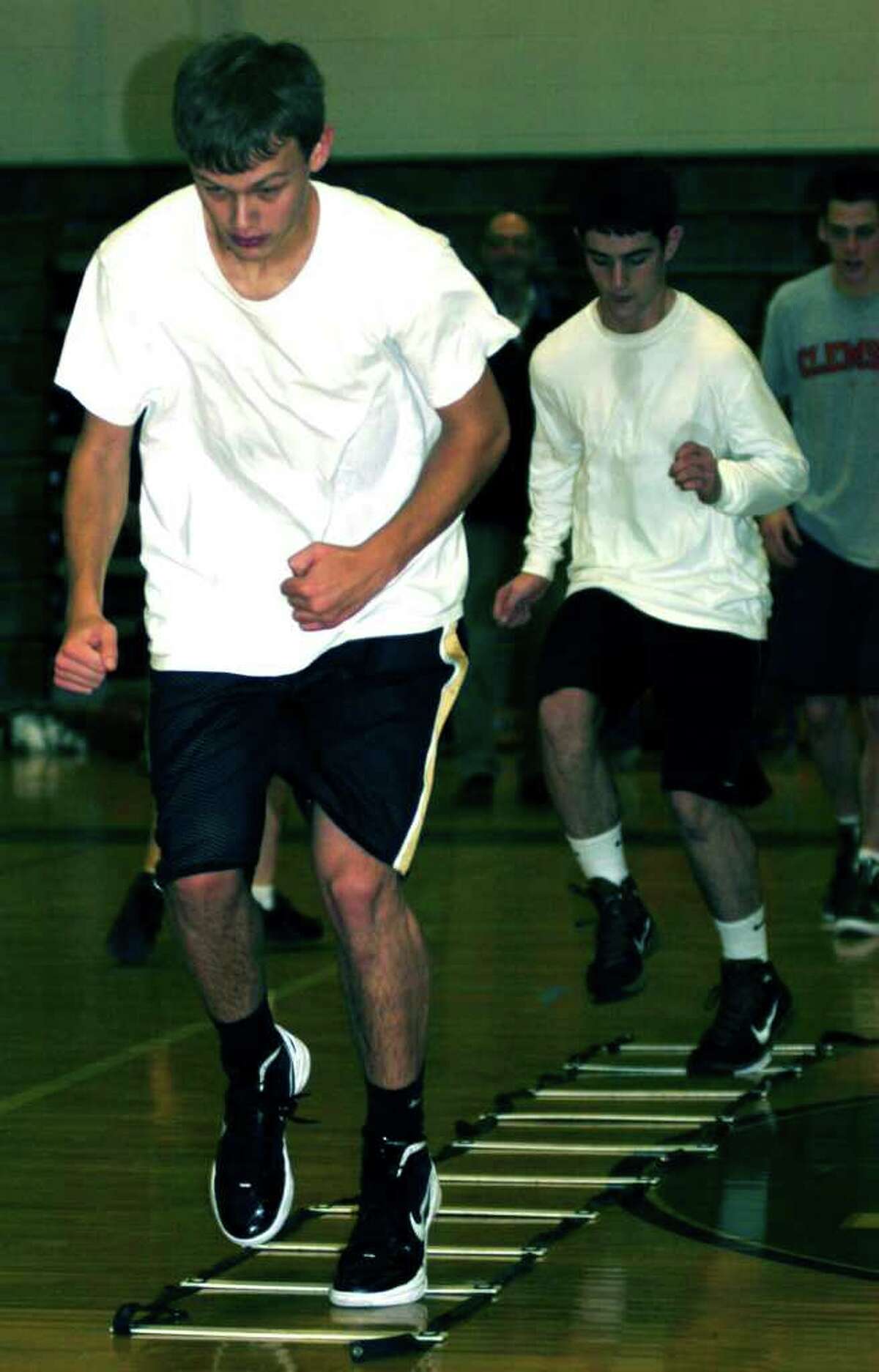 SPECTRUM/Luke Zimmerman, left, and Nick Teixeira of New Milford High School boys' basketball test themselves on an agility regimen introduced to the Green Wave by former NMHS player Chris Dzurka. December 2011