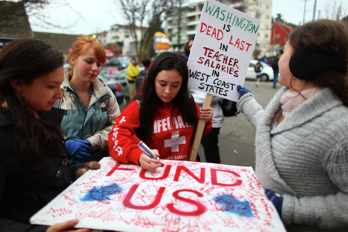 High School students sign a poster to be delivered to House Speaker Frank Chopp during a walkout by Seattle area high school students on Wednesday. The students gathered at Red Square on the UW campus and were marching to protest education cuts proposed by the state government.