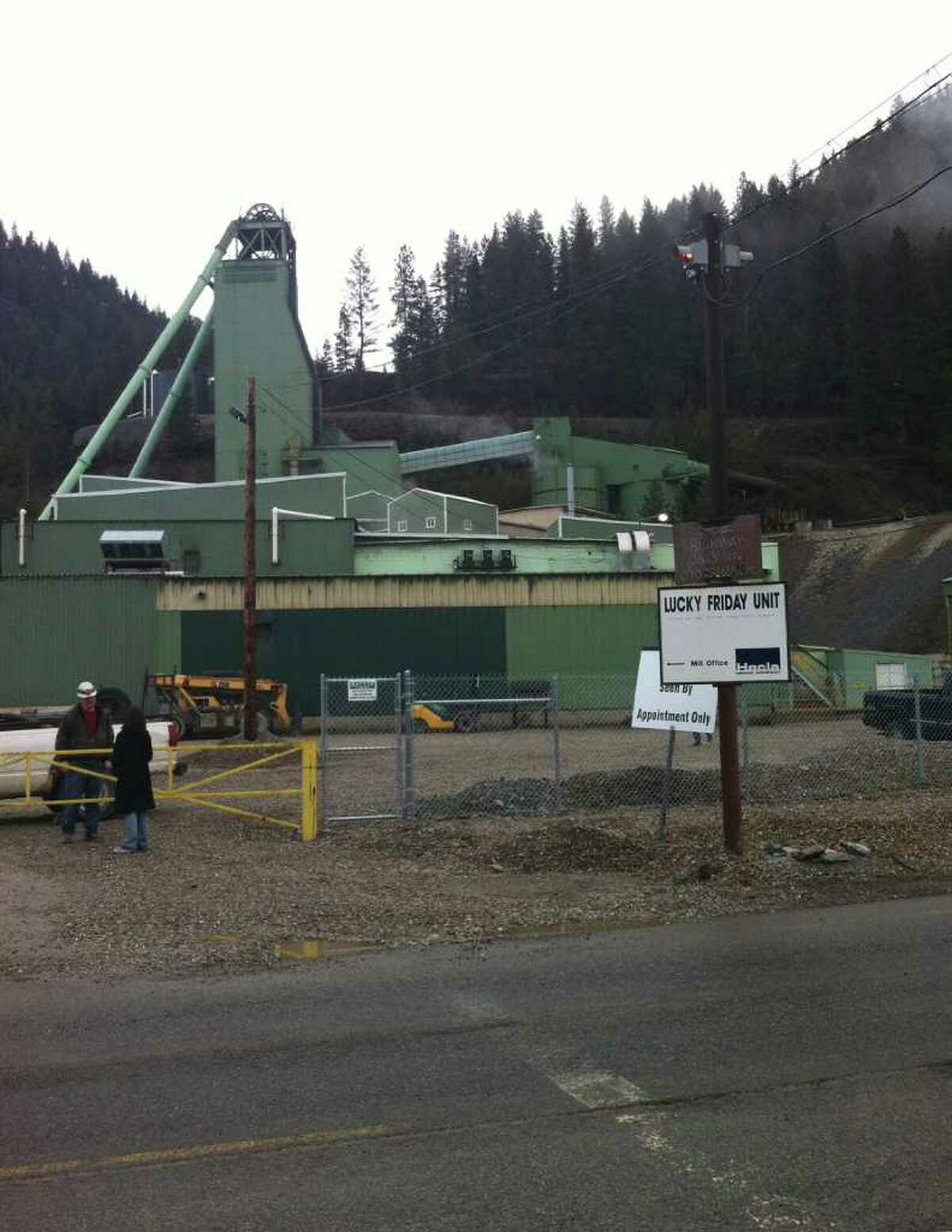 FILE - People stand at the entrance to the Lucky Friday Mine in Mullan, Idaho, in this April 16, 2011 file photo. An Idaho sheriff's officer says an underground rescue team has been sent to a mine after authorities received a report that miners have either been trapped or buried. Shoshone County sheriff's Capt. Holly Lindsey says Wednesday night Dec. 14, 2011 that it's unknown how many miners are involved or whether there are any injuries at the Lucky Friday Mine in northern Idaho. (AP Photo/KHQ-TV)