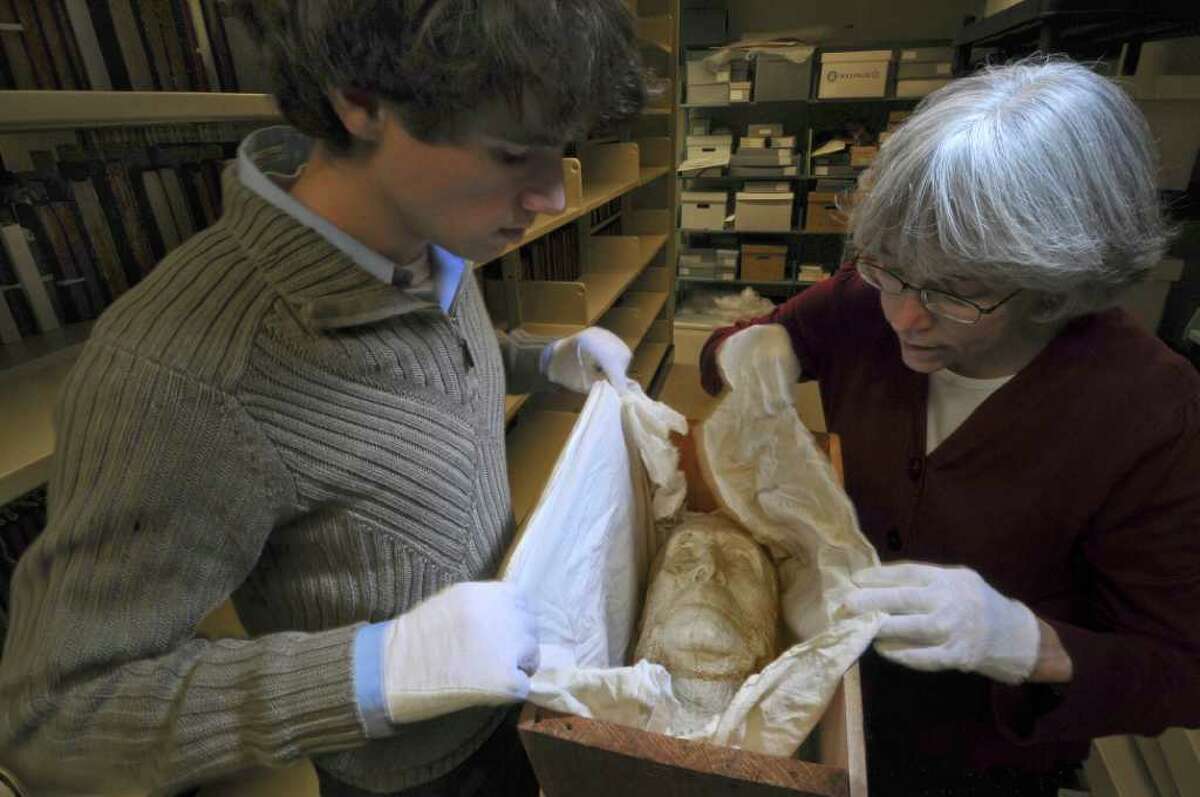Annette LeClair, librarian and head of technical services for Union College's Schaffer Library, right, and digital projects assistant Matthew Connolly, left, unwrap a plaster death mask from 1911 of Union College graduate John Bigelow, in the Special Collections storage area of the library on Tuesday Dec. 13, 2011 in Schenectady, N.Y. Bigelow was a founder of the New York Public Library, consul general to Paris for President Abraham Lincoln and a friend to Charles Dickens and other literary figures. An exhibit marking the centennial of his death begins in the library on Dec. 19. (Philip Kamrass / Times Union )