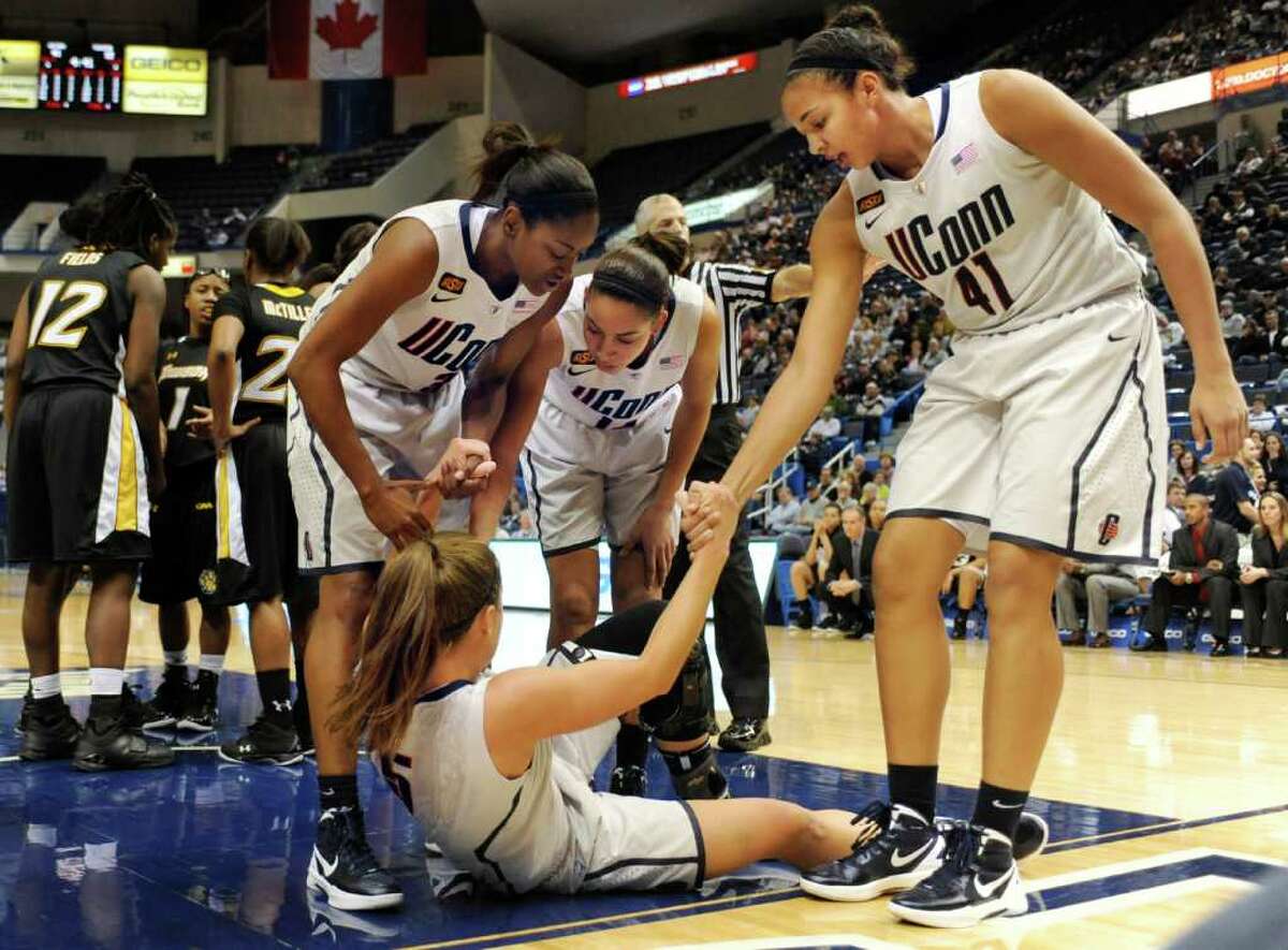 Connecticut's Caroline Doty (on floor) is helped up by teammates Tiffany Hayes, left, Bria Hartley, center, and Kiah Stokes, right, after a hard fall on a drive to the basket in the first half of an NCAA college basketball game against Towson in Hartford, Conn., Wednesday, Nov. 30, 2011. Doty did not return from the locker room at halftime and UConn officials said she had a mild head and neck injury and was staying inside to avoid the crowd noise. (AP Photo/Jessica Hill)