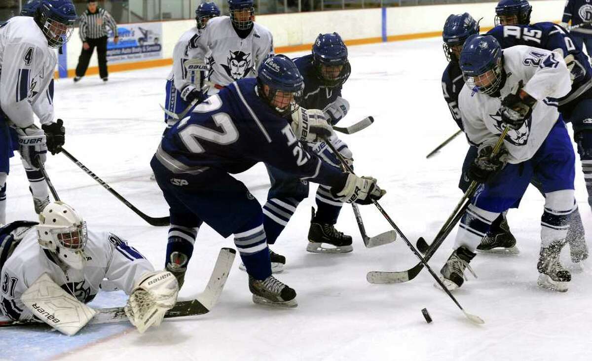 Darien's #22 George Gregory, center, tries to get to the puck as West Haven's #24 Adam Mink, right, looks to intercept, during boys hockey action in West Haven, Conn. on Saturday December 17, 2011. At left is West Haven goalie Justin Shepard.