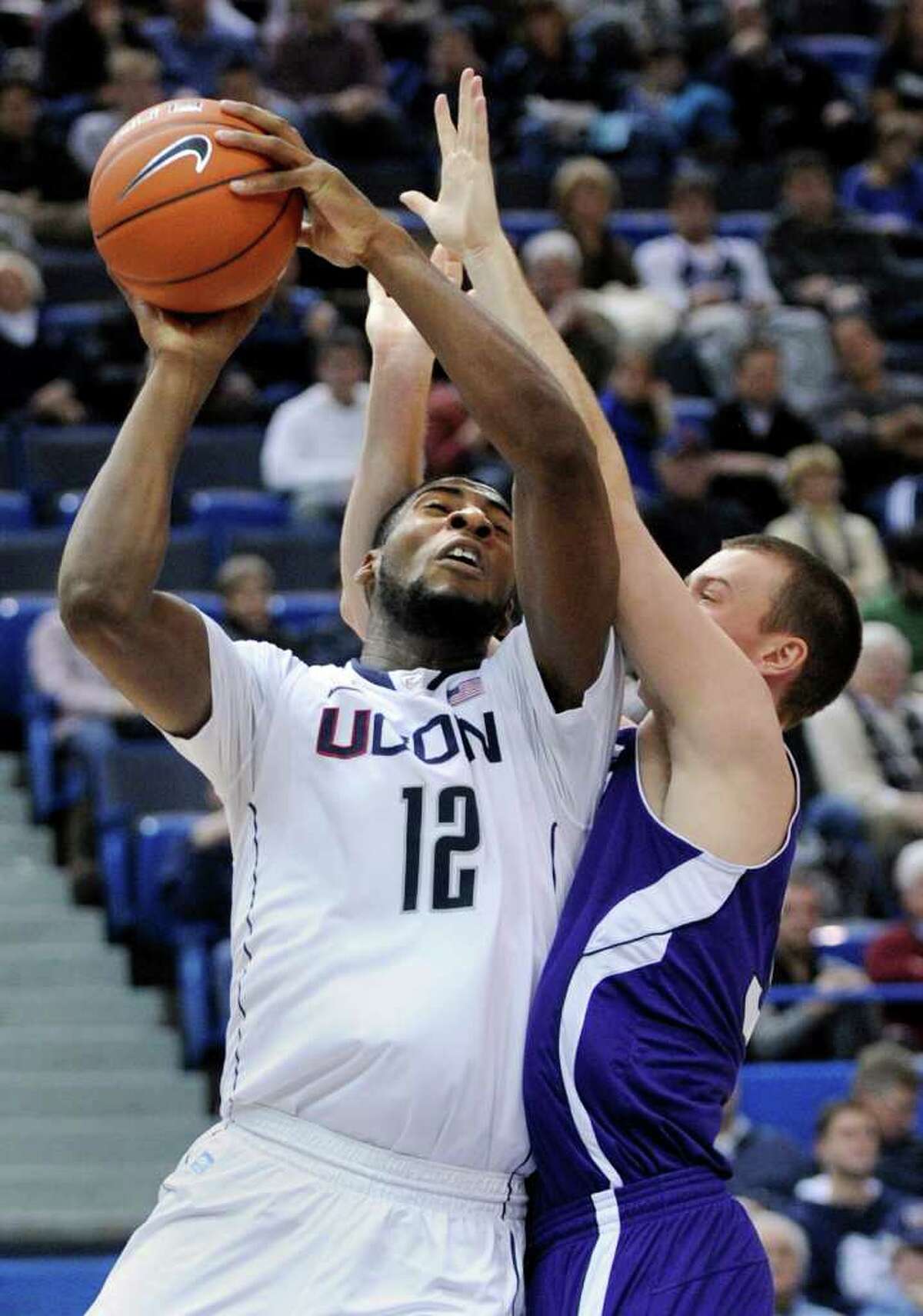 Connecticut's Andre Drummond (12) is fouled by Holy Cross' Jordan Stevens during the second half of an NCAA college basketball game in Hartford, Conn., on Sunday, Dec. 18, 2011. Drummond scored a game-high 24 points in his team's 77-40 victory. (AP Photo/Fred Beckham)