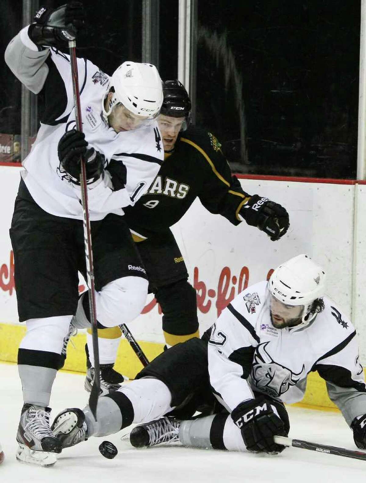The Rampage's Scott Timmins (lower right) kicks the puck to Evgenii Dadonov (left) as Texas' Jordie Benn closes in.