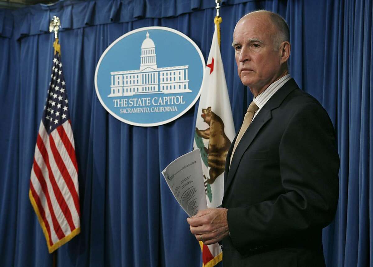 Gov. Jerry Brown listens to reporters ask Director of Finance Ana Matosantos questions about the state budget during a news conference at the Capitol in Sacramento, Calif., on Tuesday, Dec. 13, 2011. Brown said that California needs to make about $1 billion in midyear cuts to schools and social services, as the state's revenues fell about $2.2 billion below the assumptions included in the budget he signed last summer.(AP Photo/Steve Yeater)