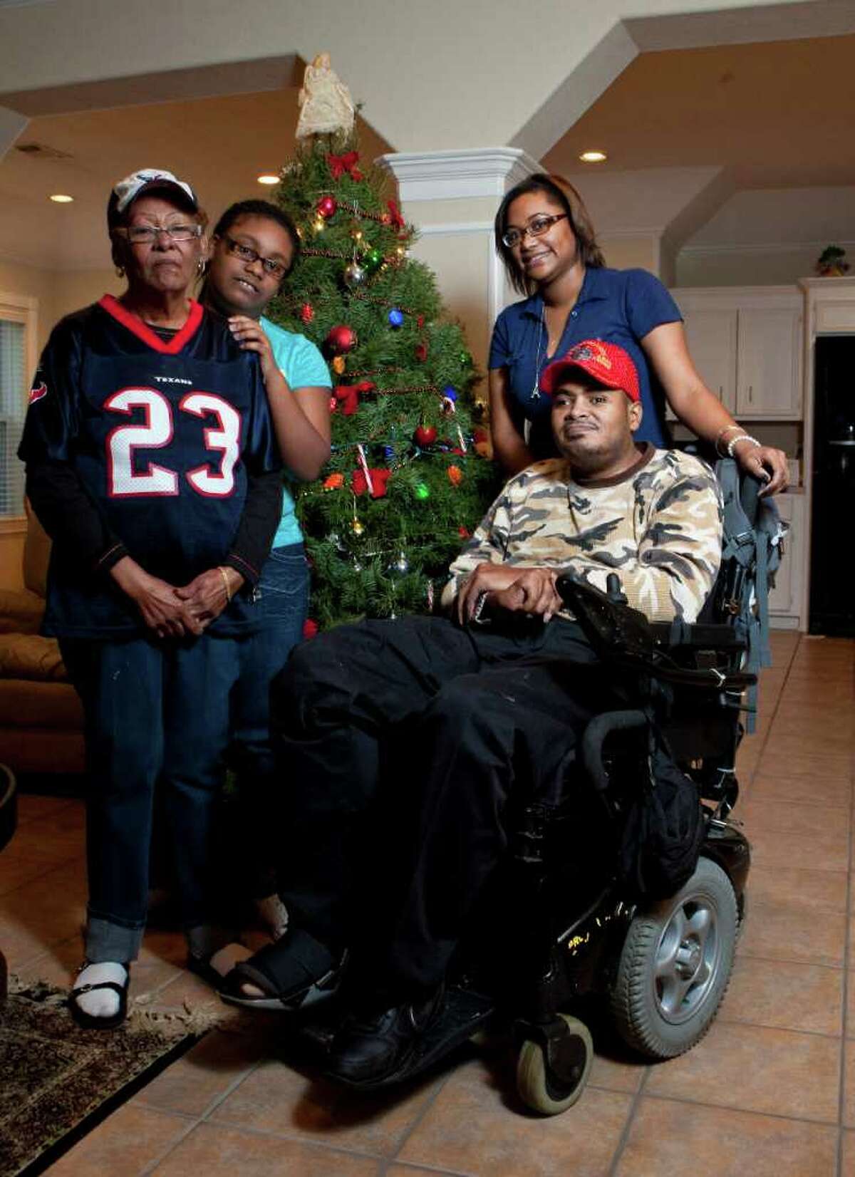 Leland Spencer, sitting, shows his Christmas tree with his mother Shirley German, left, niece Miracle Lavergne, center, and niece Krysten German, Friday, Dec. 16, 2011, in his Houston home.