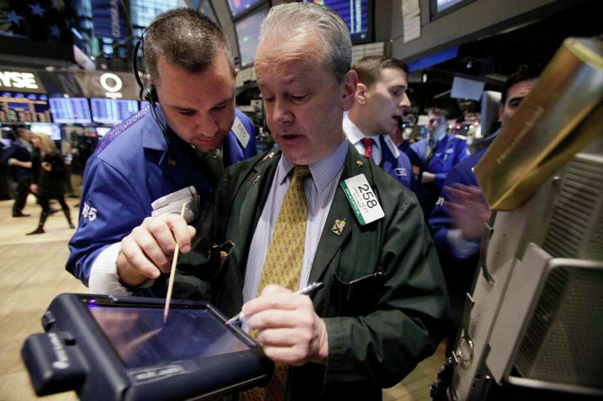 Traders James Lodewick, left, and James Riley, center, on the floor of the New York Stock Exchange Tuesday, Dec. 20, 2011. Stocks are surging after the opening bell following encouraging signs out of Europe and a jump in apartment building in the U.S. (AP Photo/Richard Drew)