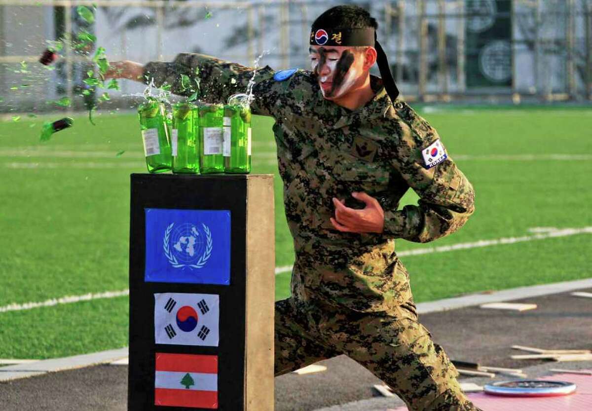 A Korean soldier breaks glass during a ceremony awarding those who spent three months carrying out duties in Tayrdebba, Lebanon, Tuesday, Dec. 20, 2011. North Korea's young and inexperienced next leader will lean on a seasoned inner circle headed by his aunt and uncle to guide him through the transition to supreme ruler. Kim Jong Un, who vaulted into the leadership role with the death of his father, Kim Jong Il, made his public debut as anointed successor only 15 months ago. (AP Photo/Mohammed Zaatari)