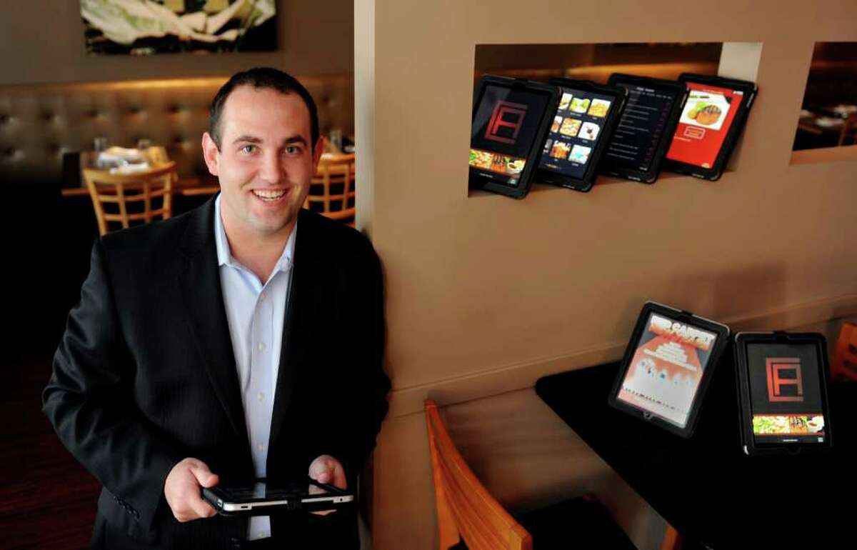 Brian Wolcott, vice president of Maxx Menu, stands in Carl Anthony's Trattoria in Monroe with the digital menus that his company provides the restaurant. The tablet-like menus offer pictures and descriptions of menu items along with beverage pairing options.