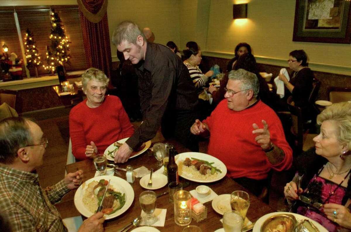Server Christopher Fayette brings out dinner for, from left, Joe and Jean Rosato, Tony and Rosemarie Abramo, at Jim Barbarie's Restaurant in Danbury on Wednesday, Dec. 21, 2011. Tony Abramo says he and his wife have been coming to the restaurant since it opened 50 years ago. He says, "Nothing beats this place."