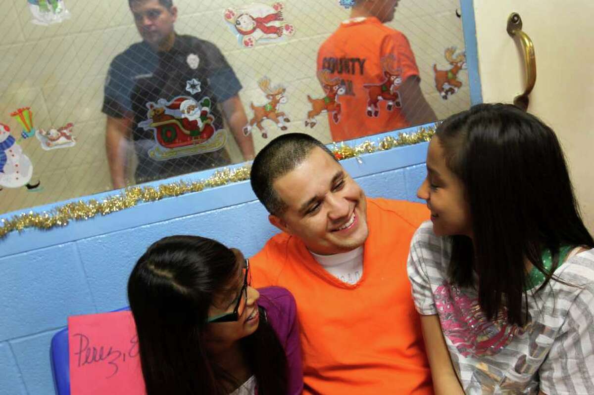 Eugene "Geno" Perez, 39, most recently arrested on drug charges, greets his daughters who are 13 and 12, as he arrives at the annual Christmas celebration for Papas and Their Children, at the Bexar County Jail Annex, Thursday, December 15, 2011. This will be Perez's third Christmas in jail. PATCH has been hosting Christmas for incarcerated fathers and their children at the Bexar County Jail since 1993. Inmates who maintain good behavior and are accepted in the PATCH program attend numerous parenting classes and, in return, earn a one-hour visit with their child or children bi-monthly.