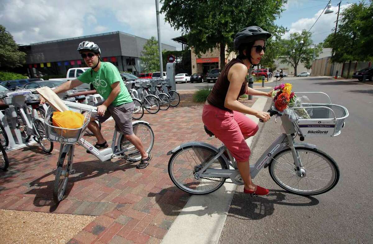 Claudia Zarazua, right, and Ruben Mancha grab bikes from a kiosk in San Antonio. The couple got rid of their car two years ago and regularly use the bikes.