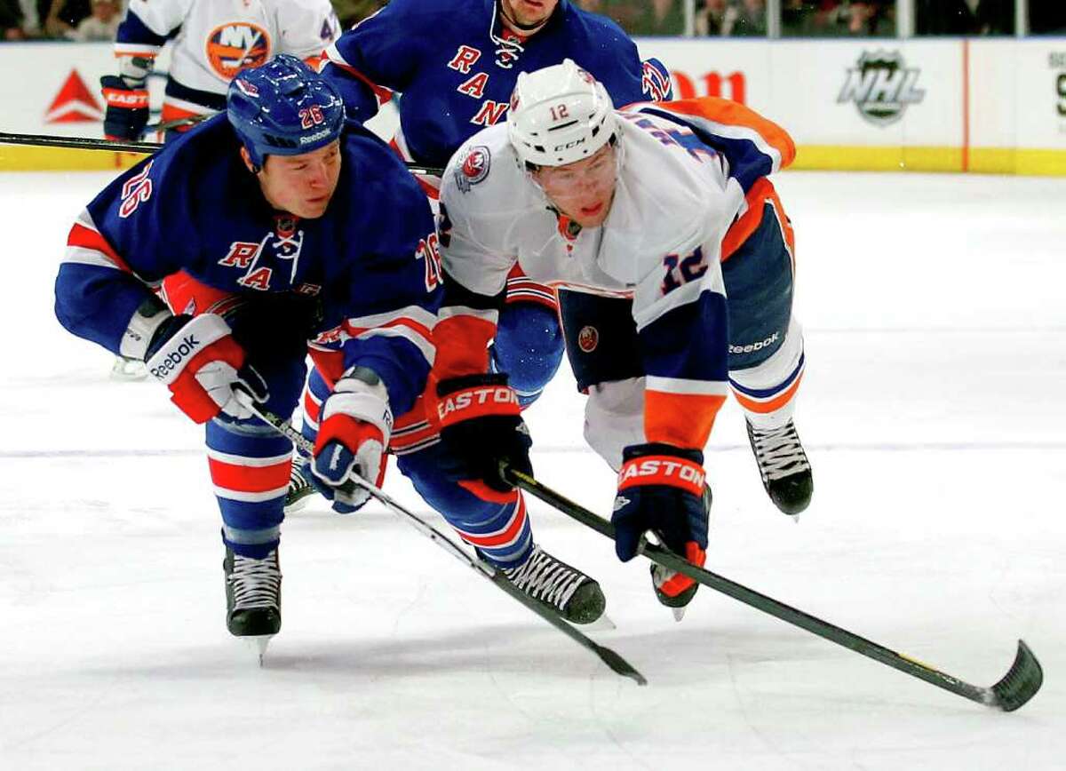 NEW YORK, NY - DECEMBER 26: Josh Bailey #12 of the New York Islanders is checked off the puck by Ruslan Fedotenko #26 of the New York Rangers in the first period of an NHL hockey game at Madison Square Garden on December 26, 2011 in New York City. (Photo by Paul Bereswill/Getty Images)