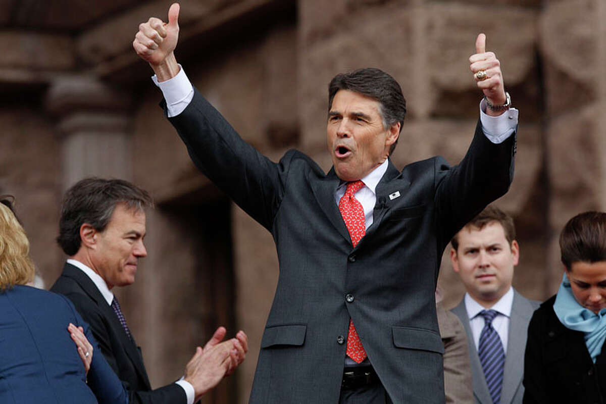 Texas Governor Rick Perry, right, reacts to the cheers of the crowd after his is sworn-in by Supreme Court of Texas Chief Justice Wallace B. Jefferson during the 2011 Texas Inauguration Oath of Office Ceremony on the South Steps of the Texas Capitol in Austin, Tuesday, Jan. 18, 2011. It is Perry's fourth oath ceremony and Lt. Gov. David Dewhurst took the oath for a third term.