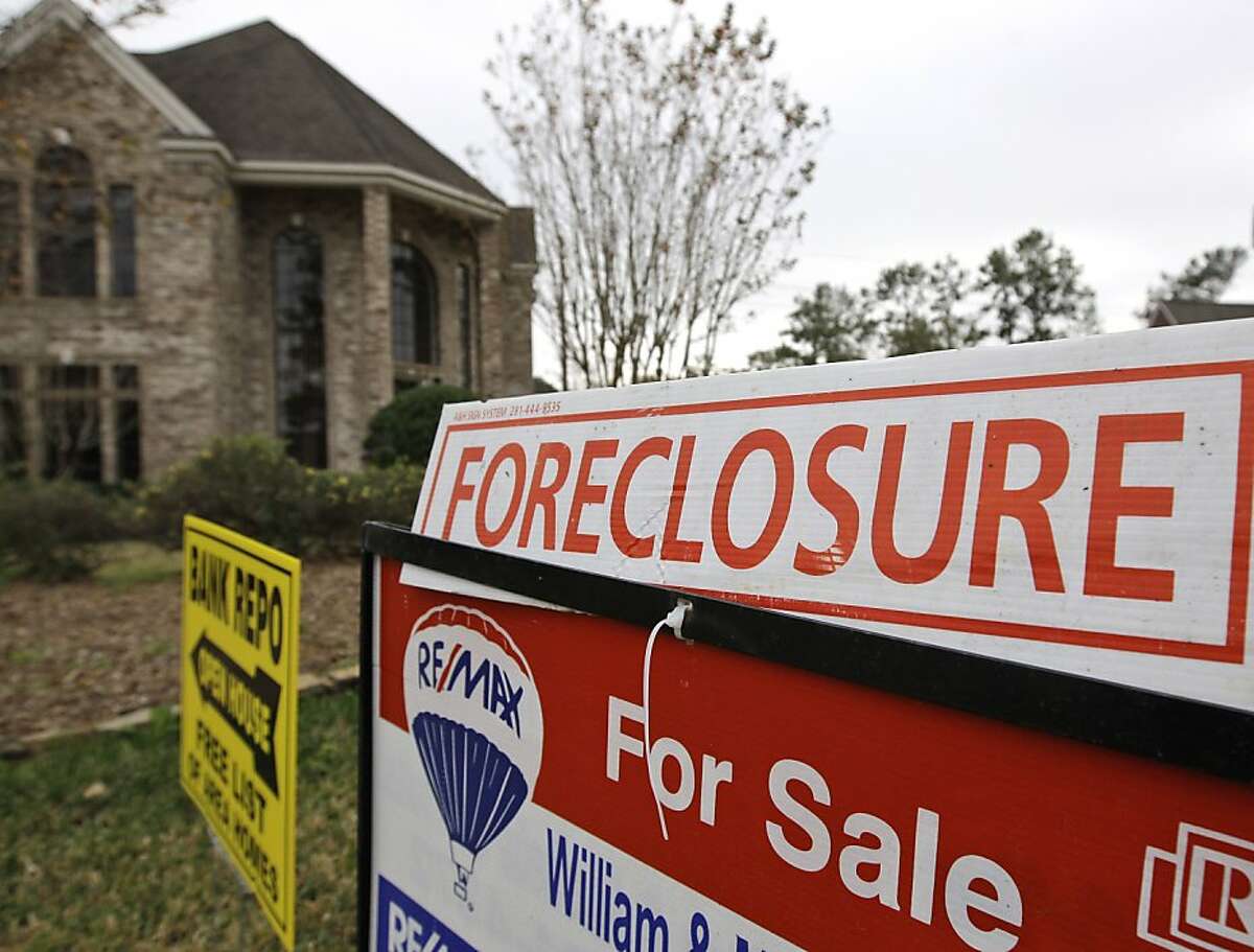 FILE - A Jan. 10, 2009 file photo shows a bank repo and foreclosure for sale signs outside a foreclosed home in Houston. Foreclosure sales plunged 25 percent in the July-September quarter versus the April-June period and tumbled 31 percent from the third quarter last year, foreclosure listing firm RealtyTrac Inc. said Thursday, Dec. 2, 2010.