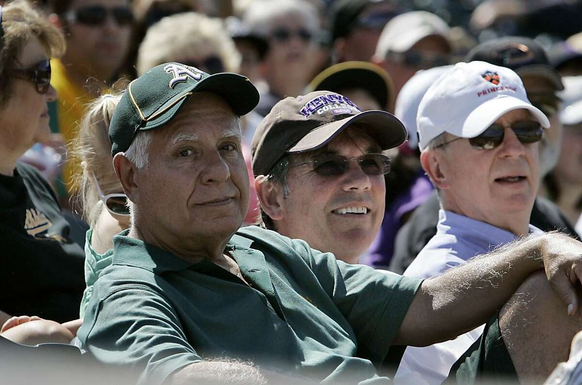 In this March 31, 2010, photo, Oakland Athletics owner and managing partner Lew Wolff, left, and general manager Billy Beane, center, watch as the Athletics played the Cincinnati Reds in a spring training baseball game in Phoenix. Wolff has been waiting two years for his old fraternity brother, commissioner Bud Selig, to tell him whether he can go ahead with his outline to move the A's from Oakland into Santa Clara County even though the San Francisco Giants hold the territorial rights in technology-richSilicon Valley.