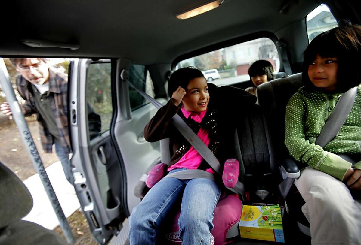 Twins Greer, left, and Scarlet Nakadegawa-Lee, 7, get settled in their booster seats before heading out in Oakland, Calif., Thursday, December 29, 2011. Their father, Tadashi Nakadegawa, left, is happy the child safety seat laws have been extended. The girls will now have to stay in the seats until they are eight, and he thinks this will keep them safer.
