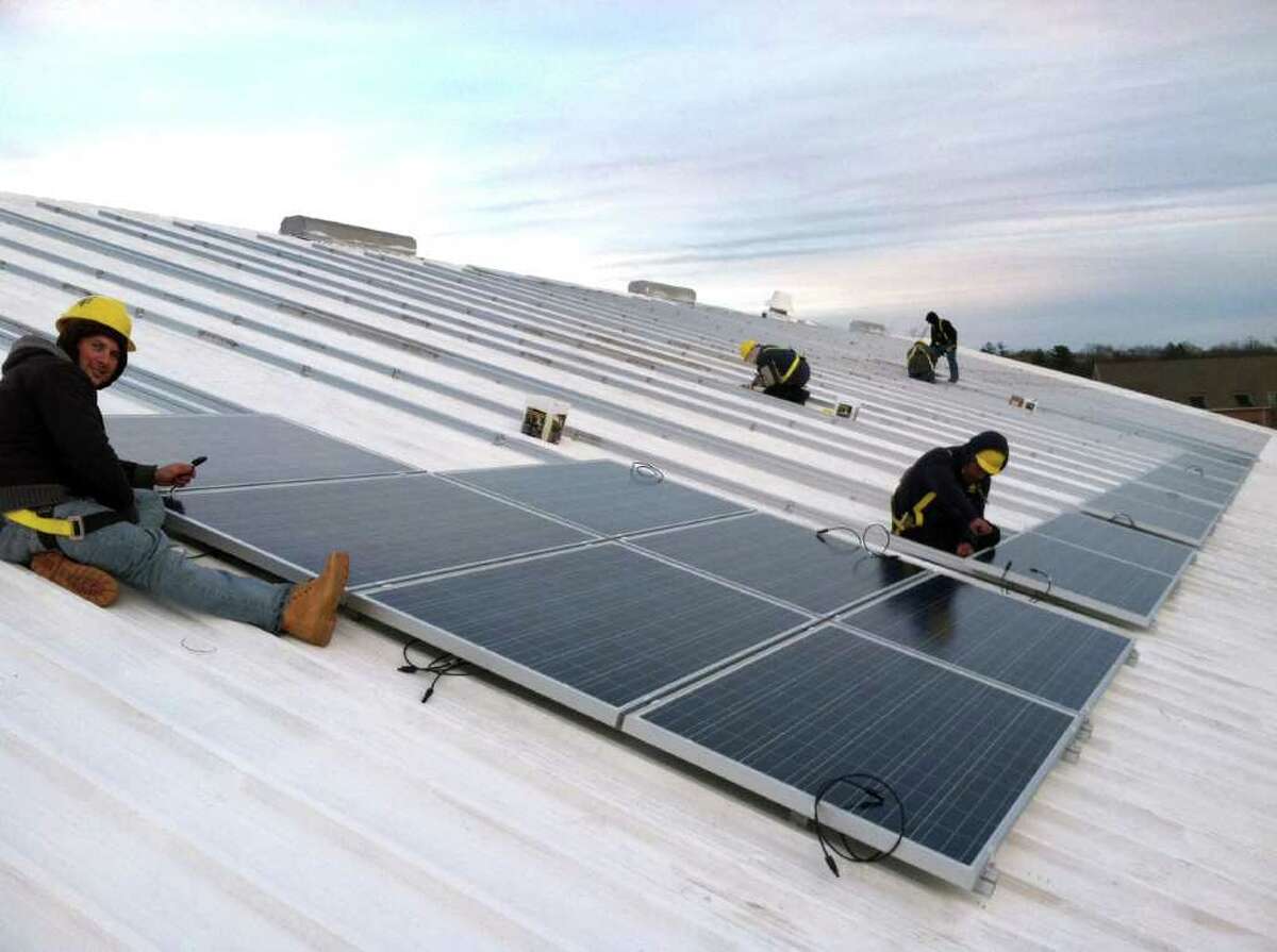 Workers install solar panels on the roof of the Greenwich Racquet Club on River Road in Cos Cob. The project, designed and overseen by Greenwich-based Sound Solar Systems, should be completed by the end of February.