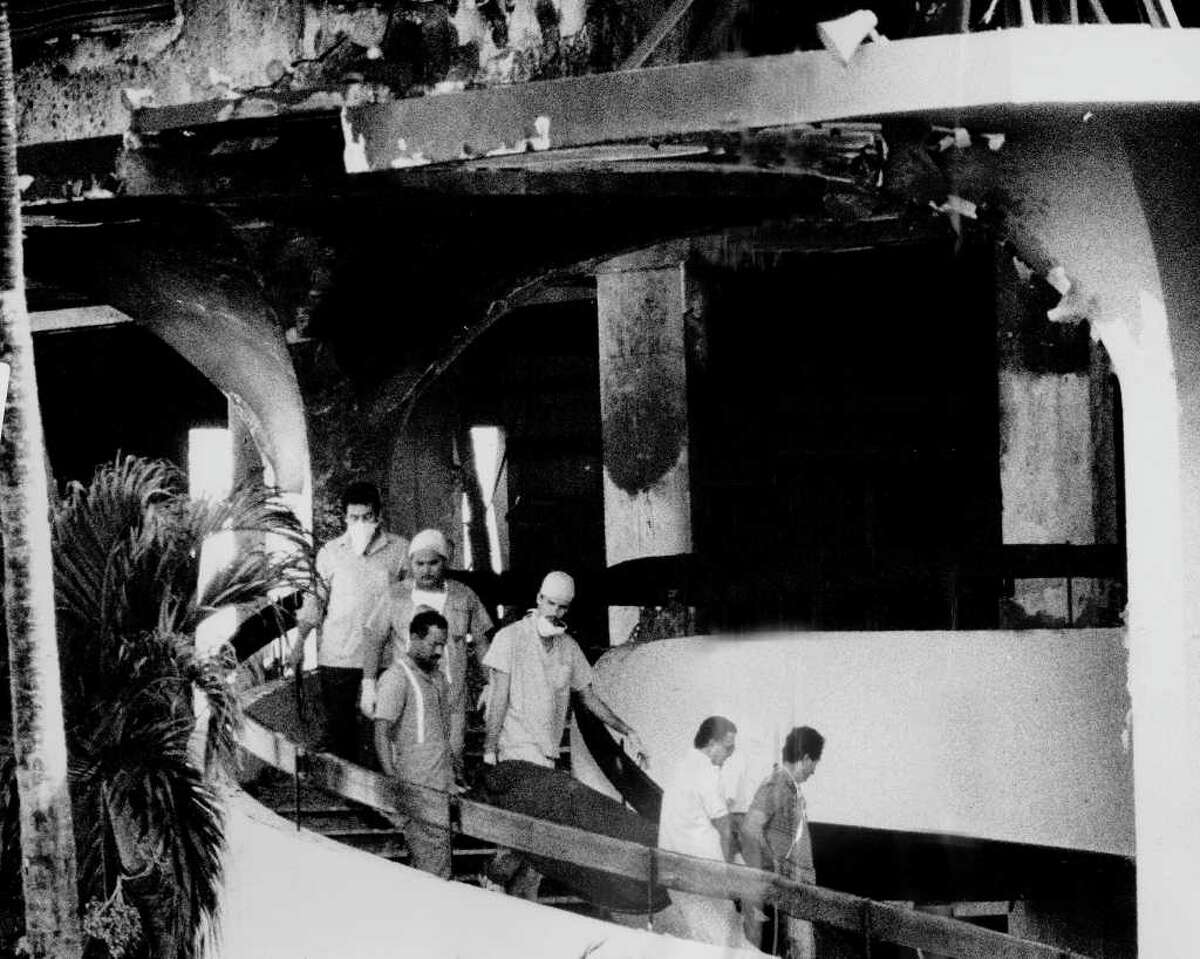PUERTO RICO - JANUARY 01: Victim of New Year's Eve inferno is carried down winding staircase of the Dupont Plaza Hotel. Many more are still believed to be still inside. Gov. Rafael Hernandex Colon said he suspects arson because of recent threats against hotel. (Photo by Misha Erwitt/NY Daily News Archive via Getty Images)