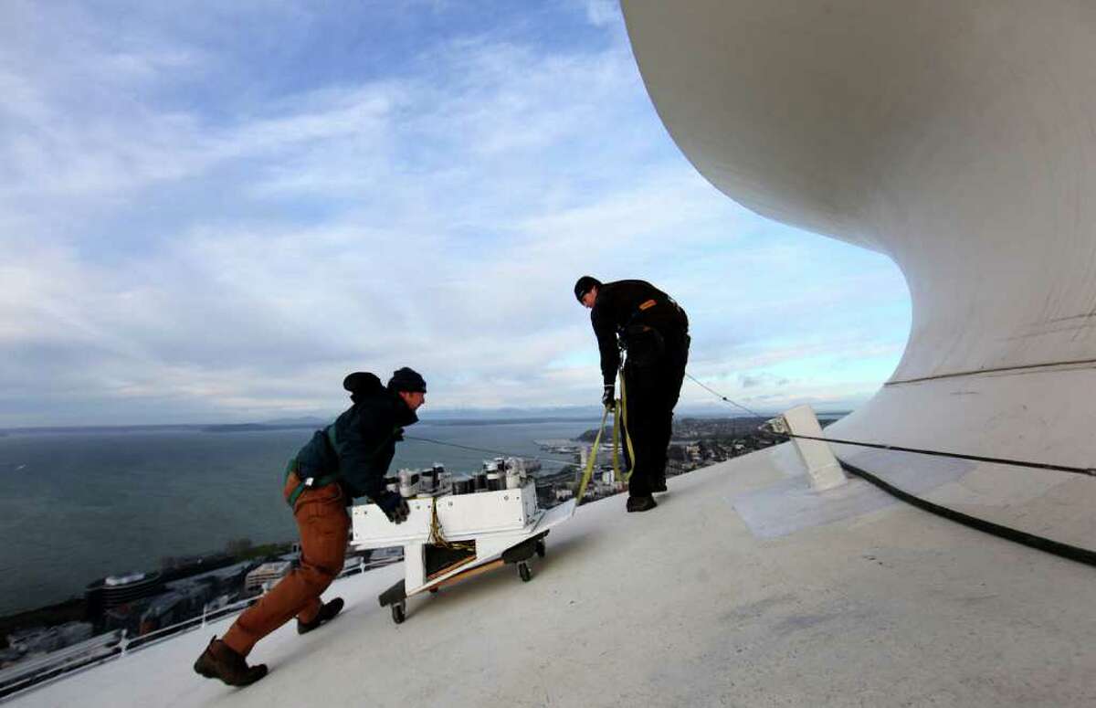 Scott Streeper, left, and Matt Gilfillan prepare to place fireworks on the roof of the Space Needle as a crew prepares for the annual New Years firework display. The crew started placing fireworks on the iconic Seattle landmark on Wednesday, December 30, 2011.