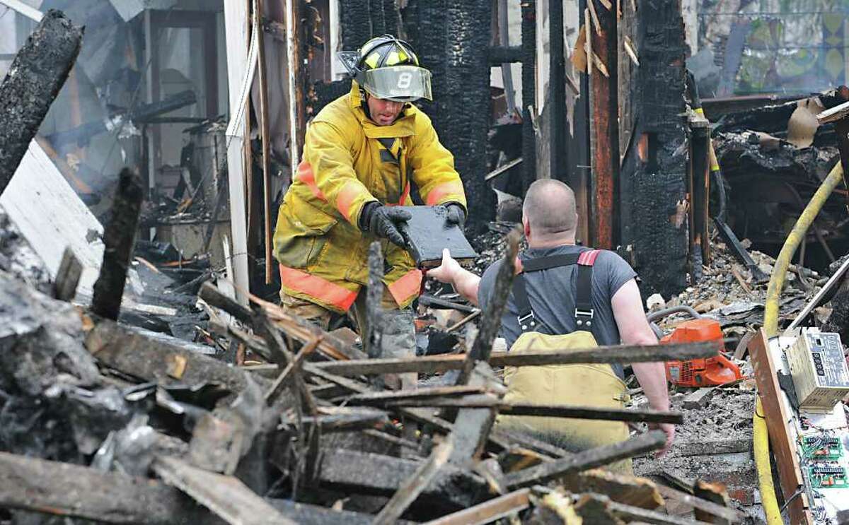 Firefighter Dave Tabor hands off Rev. Orth's Bible to firefighter Jim Yager in the smoldering rubble of a fire at Mayfield Central Presbyterian Church in Mayfield, N.Y. on April 28, 2011. The only part of the bible that endured water damage was the tassel. (Lori Van Buren / Times Union)