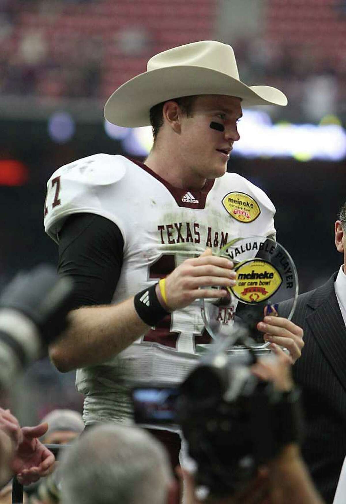 Texas A&M Aggies quarterback Ryan Tannehill (17) wears a cowboy hat as he holds the MVP trophy after the Meineke Car Care Bowl at Reliant Stadium,Saturday, Dec. 31, 2011, in Houston. Texas A&M won the game against Northwestern University 33-22.