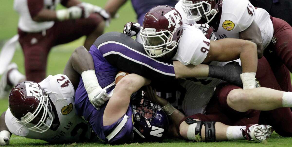 Northwestern running back Jacob Schmidt, center, is crushed by Texas A&M's Kirby Ennis (42), Damontre Moore (94), and Steven Jenkins (45) during the first quarter of the Car Care Bowl NCAA college football game Saturday, Dec. 31, 2011, in Houston.