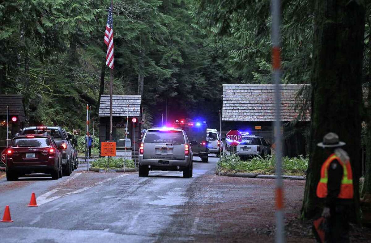 Emergency vehicles speed to the scene of a shooting of a Mount Rainier National Park ranger as another ranger redirects traffic in Mount Rainier, Wash., Sunday, Jan 1, 2012. A Mount Rainier National Park ranger was fatally shot following a New Year's Day traffic stop and authorities believed the gunman was still in the woods with an assault rifle.