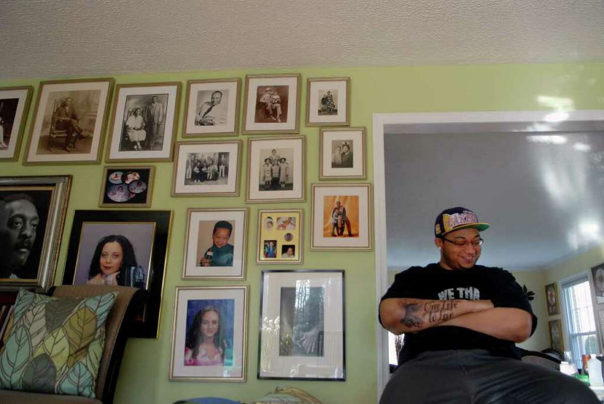 Atiba MacDonald (22), the son of Ralph MacDonald a Stamford musician who recently passed away, sits by a wall of family photos in their Stamford, Conn. home on Thursday December 29, 2011.
