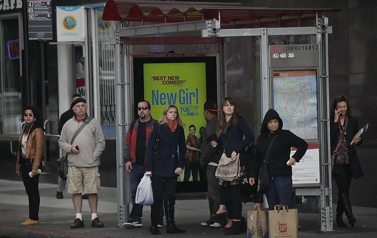People wait at a bus stop on Van Ness Avenue at Market Street for the arrival of a bus on Tuesday, January 3, 2012 in San Francisco, Calif.