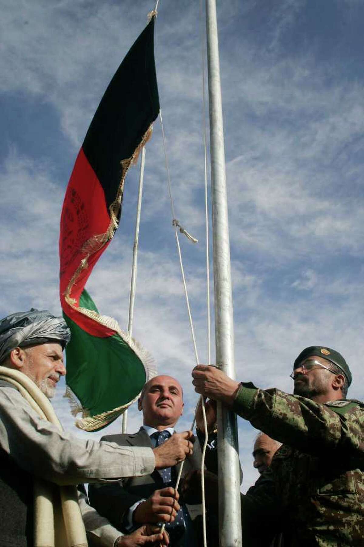 Ashraf Ghani Ahmadzai, left, head of the Transition Commission, raises the Afghanistan flag during the transfer of authority from NATO troops to Afghan security forces in Chaghcharan, Ghor province, west of Kabul, Afghanistan, Wednesday, Jan. 4, 2012. The security responsibilities of Chaghcharan, the provincial capital of Ghor province is handed over from the NATO forces to Afghan security forces. The process of taking over security from over 130,000-strong NATO-led ISAF forces by Afghan troops would be completed by the end of 2014 when Afghanistan will take over the full leadership of its own security duties from U.S. and NATO forces. (AP Photo/Hoshang Hashimi)