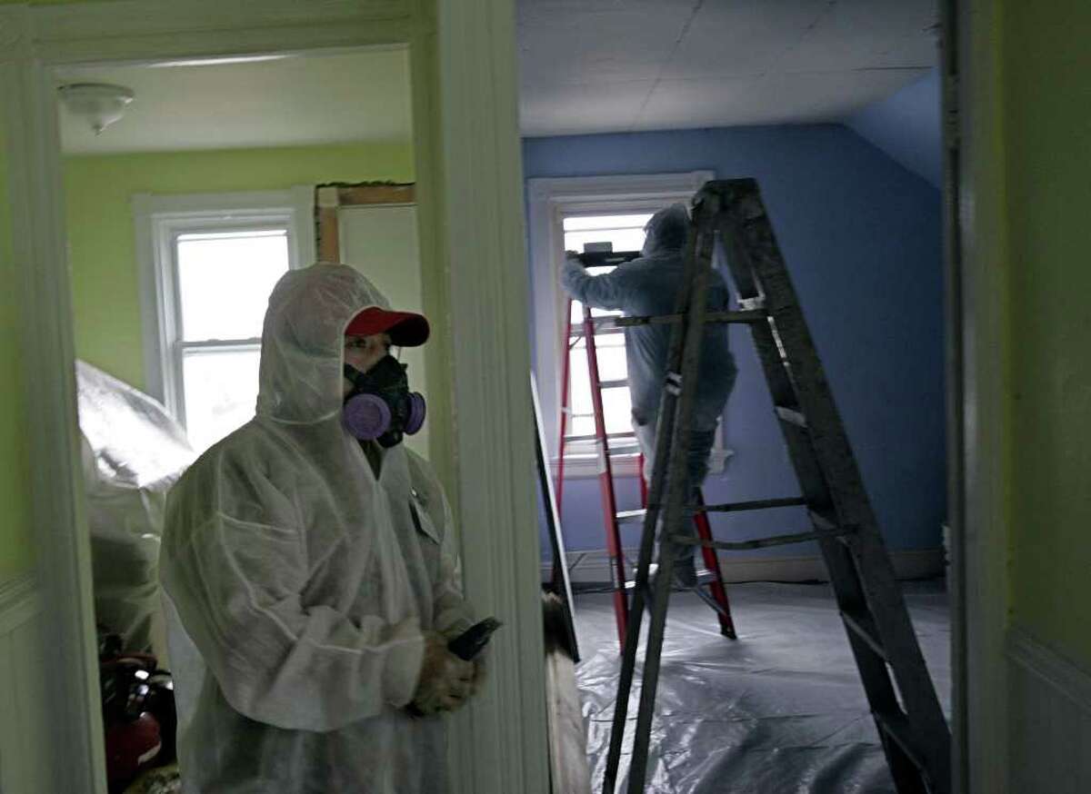 In this Thursday, Feb. 23, 2006 photo, contractors Luis Benitez, foreground, and Jose Diaz, background, clean up lead paint in a contaminated building in Providence, R.I. A federal panel recommended Wednesday, Jan. 4, 2012 that the threshold for lead poisoning in children should be lowered. If adopted by government officials, hundreds of thousands of additional U.S. children could be classified as having lead poisoning. Recent research persuaded panel members that children could suffer harm from concentrations of lead lower than the old standard, Centers for Disease Control and Prevention officials said. (AP Photo/Chitose Suzuki)