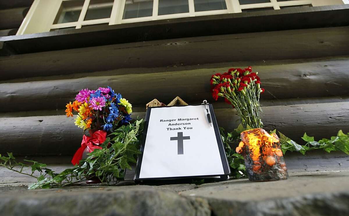 Flowers stand next to a small memorial book for Mount Rainer National Park Ranger Margaret Anderson at the Nisqually entrance to the park Tuesday, Jan. 3, 2012, near Ashford, Wash. The park remained closed while the investigation continued a day after searchers found the body of the gunman suspected of shooting and killing Anderson on Sunday. Benjamin Colton Barnes was lying partially submerged in a frigid mountain creek with snow banks standing several feet high on each side. (AP Photo/Elaine Thompson)