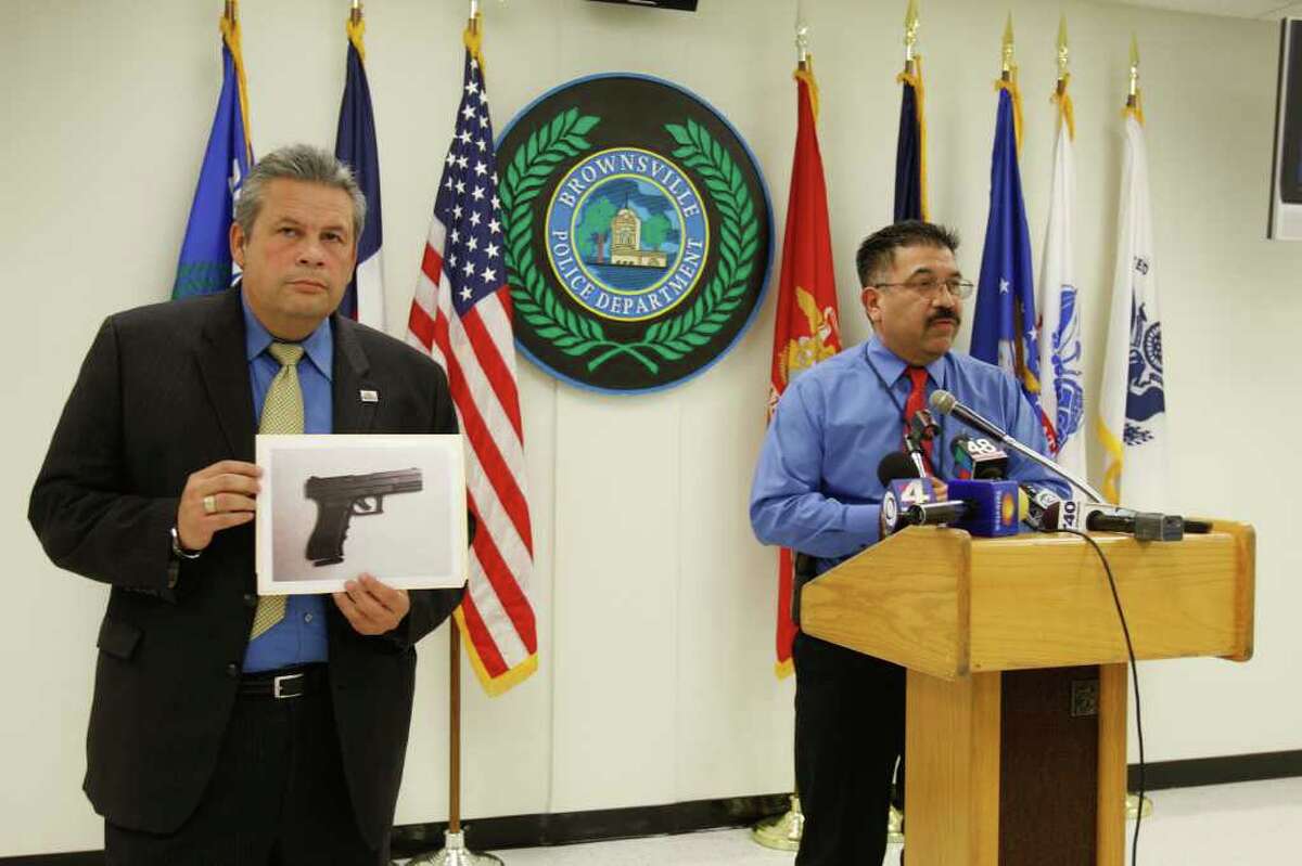 Brownsville City Manager Charlie Cabler, left, shows a photo of the Glock-like air gun. Police Chief Orlando Rodriguez says the boy refused to drop the pistol.