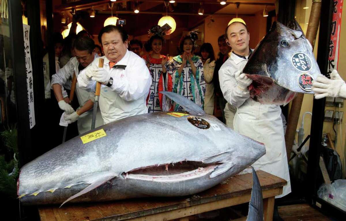 Kiyoshi Kimura, president of Kiyomura Co., left, cuts a bluefin tuna in front of his Sushi Zanmai restaurant near Tsukiji fish market in Tokyo Thursday. The bluefin tuna caught off northeastern Japan was sold at a record 56.49 million yen, or about $736,000.