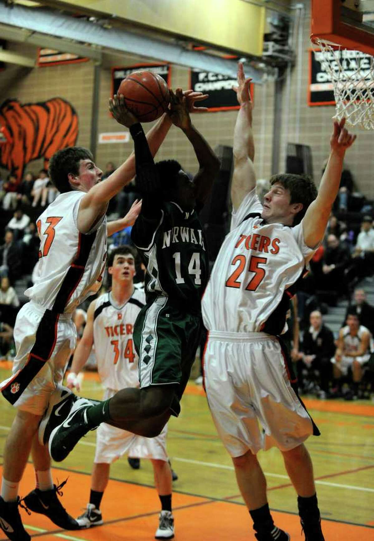 Norwalk's Jabari Dear drives to the basket while under pressure from Ridgefield's Patrick Racy, left, and Chipper McClelland during their game at Ridgefield High School on Friday, Jan. 6, 2012. Ridgefield won 60-40.