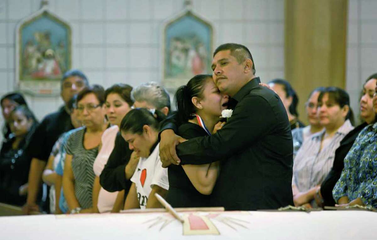 Jaime Gonzales Sr. embraces his wife near the casket of his son at Holy Family Church in Brownsville on Saturday. Police fatally shot the eighth-grader, who was brandishing what appeared to be a handgun.