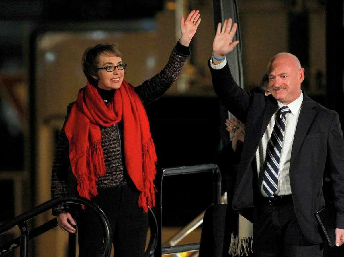 Rep. Gabrielle Giffords (left) and her husband, former astronaut Mark Kelly, wave at the start of a memorial vigil remembering the victims and survivors one year after the shooting rampage targeting Giffords, and killing 6 other people.