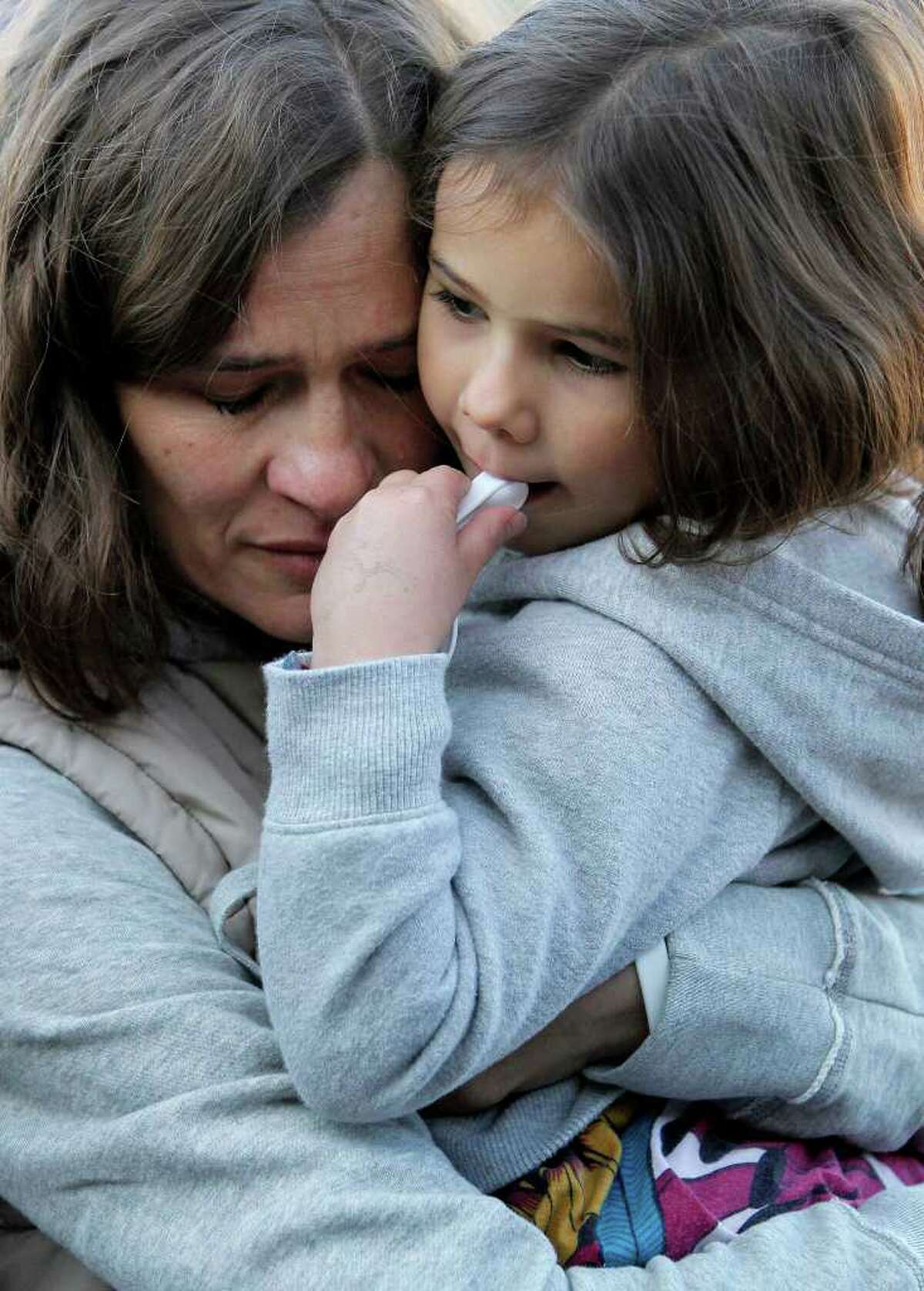 Ina Menzl, left, hugs her daughter, 4-year-old Rebecca Kraft, Sunday, Jan. 8, 2012, in Tucson, Ariz., outside the Safeway grocery store where U.S. Rep. Gabrielle Giffords, D-Ariz., was shot one year ago during a shooting spree that left 6 dead and 13 wounded, including Giffords. (AP Photo/Matt York)