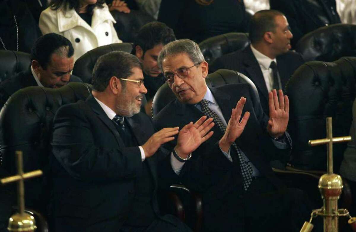 FILE - In this Friday, Jan. 6, 2012 file photo, Mohamed Morsi, left, of Egypt's Muslim Brotherhood and Egyptian presidential hopeful Amr Moussa, right, talk before Christmas Eve mass, led by Coptic Pope Shenouda III at the Coptic cathedral in Cairo, Egypt. The Muslim Brotherhood has emerged as the biggest winner in parliamentary elections, but the fundamentalist group that has long dreamed of ruling Egypt is likely to be cautious about flexing its newfound muscle.(AP Photo/Maya Alleruzzo, File)