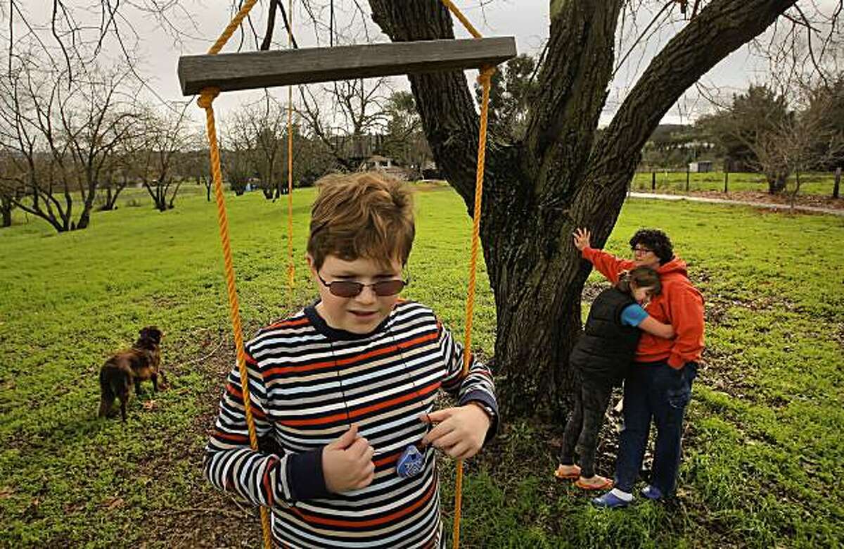 Deborah Gustlin with her daughter Hannah and Benjamin, on a swing at their Morgan Hill, Ca. home on Tuesday Dec. 21, 2010. Deborah's 12-year-old son Benjamin has Asperger's Syndrome and Deborah had to lie to get him covered on her health plan, after she was denied. She's been paying his treatment costs for Asperger's out of pocket. Her policy lifted the pre-exisisting condition denial on October 1st of this year, but she also got hit with a higher insurance rate.