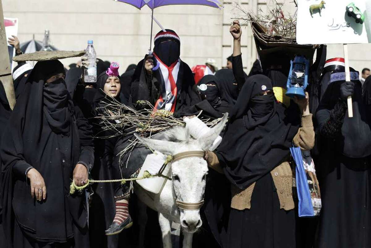 A female supporter, center, of Yemen's President Ali Abdullah Saleh rides a donkey during a rally demanding basic services from the new government in Sanaa, Yemen, Monday, Jan. 9, 2012. Arabic writing on the placard, far right, reads, "petrol." (AP Photo/Hani Mohammed)