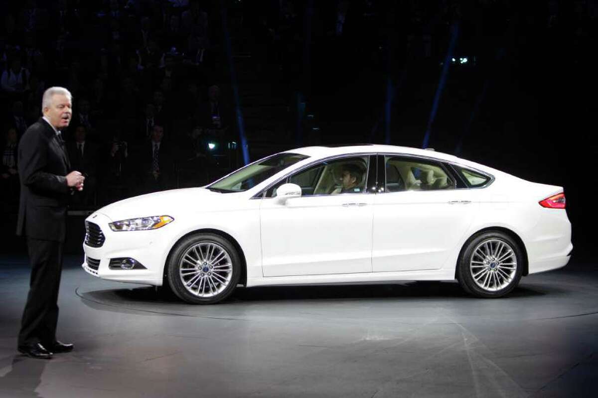 Derrick Kuzak, Ford group vice president, shares the spotlight with the revamped 2013 Ford Fusion at the North American International Auto Show in Detroit.