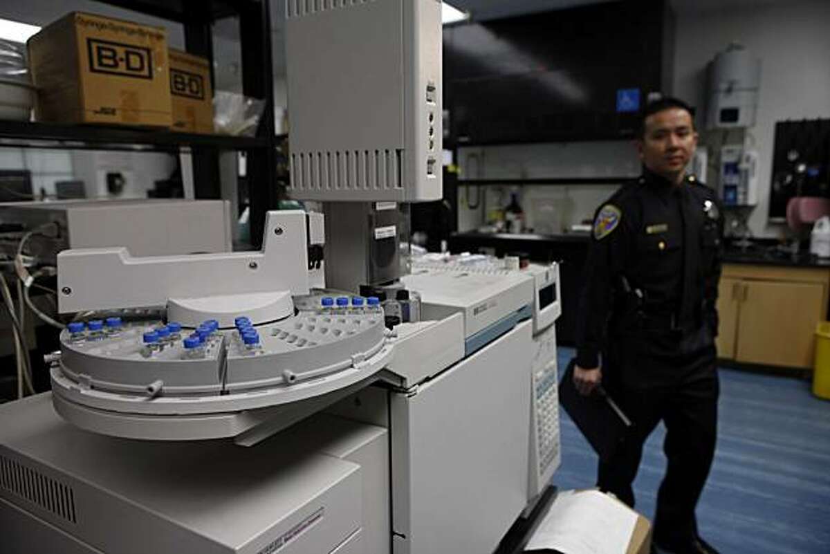 SFPD PIO Samson Chan (right) walks past equipment seen in the narcotics/chemical analysis unit during a media tour of the Crime Lab in San Francisco, Calif. on Wednesday, March 10, 2010.
