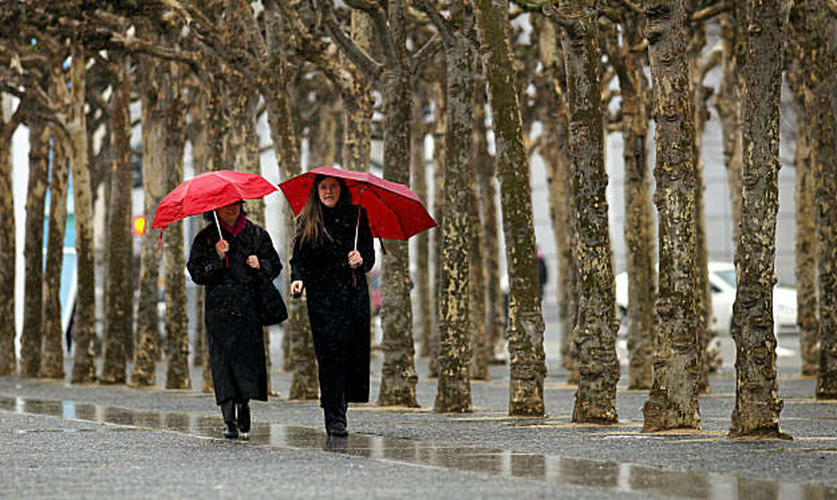 Pearl Chan, (left) and Rosanne Torre, make their way through Civic Center Plaza, back to work at City Hall on Thursday Feb. 24, 2011, in San Francisco, Ca., as the next rain begins to move through the Bay Area bringing with it colder temperatures.