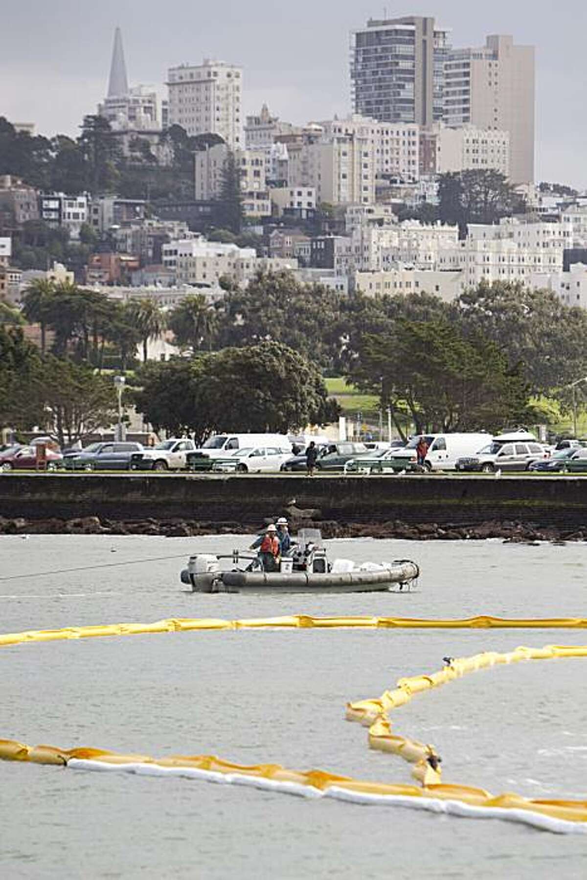 Workers put oil containment booms around a barge that ran aground in the water near the St. Francis Yacht Club in San Francisco on Tuesday. The sand transportation barge was intentionally run aground after it began taking on water and booms were put out as a precautionary measure.