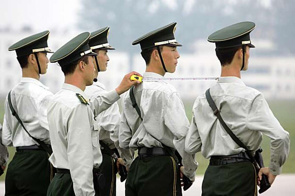 A Chinese paramilitary guard (2nd L) measures the exact space between two others as they practice their drills to prepare for the National Day march at a training center in Beijing on September 6, 2009. China is planning a huge military parade and mass pageant in and around Tiananmen Square on October 1 to celebrate 60 years of Communist rule.